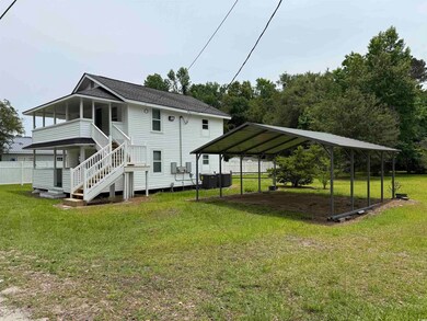 Front view of house featuring a carport, stairs, central air condition unit, a lawn, and roof with shingles