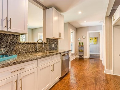 Kitchen with decorative backsplash, dark stone counters, dark wood-type flooring, white cabinets, and plenty of natural light