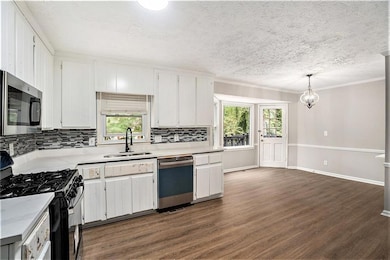 Kitchen featuring pendant lighting, white cabinets, sink, and stainless steel appliances