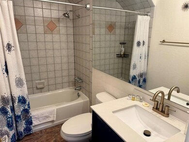 Bathroom featuring shower / bathtub combination with curtain, vanity, a textured wall, and dark tile patterned floors