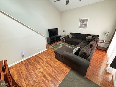 Living area featuring wood finished floors, a ceiling fan, and lofted ceiling