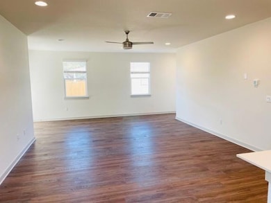 Empty room with ceiling fan, dark wood-style floo
