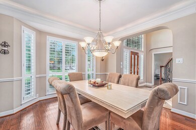 Formal dining room just off the entry offers crown molding with indirect lighting, plantation shutters, chair rail wood flooring and an elegant light fixture.
