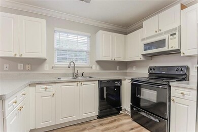 Kitchen with black appliances, a sink, crown molding, white cabinets, and light wood-type flooring
