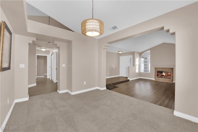 Unfurnished living room featuring lofted ceiling, carpet floors, and a tiled fireplace