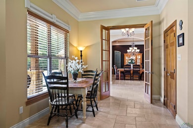 Dining area featuring a chandelier, ornamental molding, healthy amount of natural light, stone tile flooring, and french doors