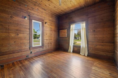 Unfurnished room featuring wooden walls, hardwood