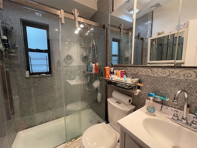 Bathroom with toilet, a shower stall, vanity, and tile walls