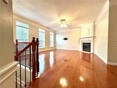 Unfurnished living room with a ceiling fan, ornamental molding, wood finished floors, baseboards, and a fireplace