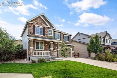 Craftsman-style house with stone siding, a front lawn, covered porch, concrete driveway, and an attached garage