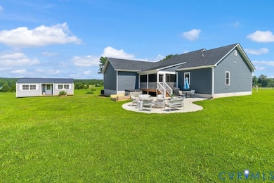 Back of house featuring a patio, a lawn, an outdoor structure, and a shingled roof