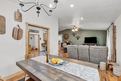 Dining area with lofted ceiling, light wood-type flooring, ceiling fan, and a chandelier