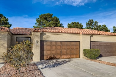 View of front facade featuring stucco siding, a tile roof, and driveway