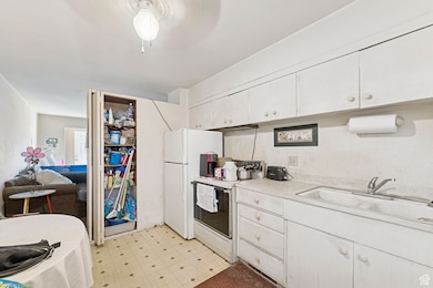 Kitchen with light countertops, white electric stove, white cabinetry, and light flooring