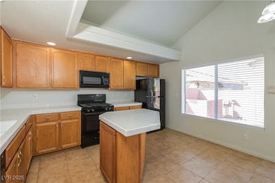 Kitchen featuring light tile patterned floors, black appliances, brown cabinetry, recessed lighting, and a kitchen island
