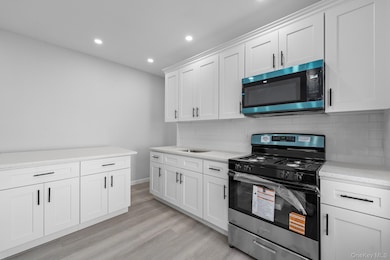 Kitchen with stainless steel gas stove, white cabinets, tasteful backsplash, recessed lighting, and light wood-type flooring