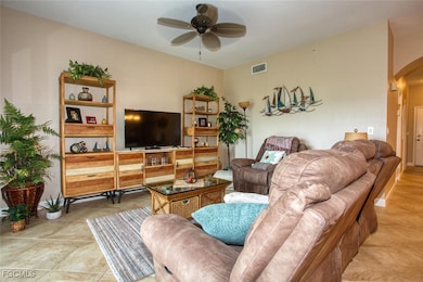 Living room with arched walkways, light tile patterned flooring, and a ceiling fan