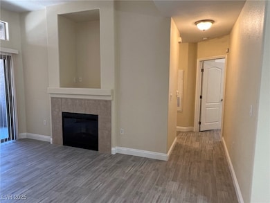 Unfurnished living room featuring wood finished floors and a tiled fireplace