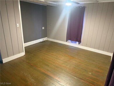 Unfurnished room featuring dark wood-style floors, ceiling fan, and wood walls
