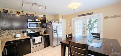 Kitchen with stainless steel appliances, light countertops, decorative backsplash, and light tile patterned floors