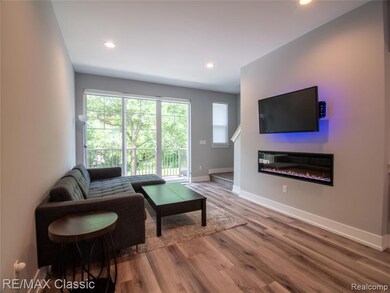 Living area featuring a glass covered fireplace, wood finished floors, and recessed lighting