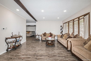 Living area with recessed lighting, dark wood-style floors, a textured ceiling, and beamed ceiling