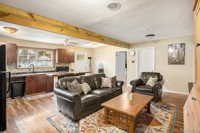 Living area with beam ceiling, dark wood-type flooring, and a ceiling fan