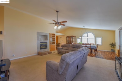 Carpeted living area with vaulted ceiling, a tile fireplace, and ceiling fan