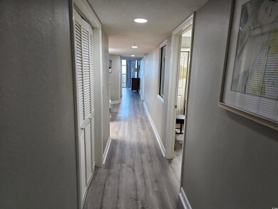 Corridor featuring light wood-type flooring and ba