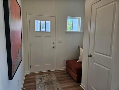 Foyer with dark wood-type flooring and baseboards