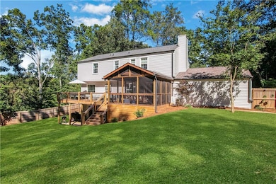 Back of house with a sunroom, a deck, a chimney, and stairs