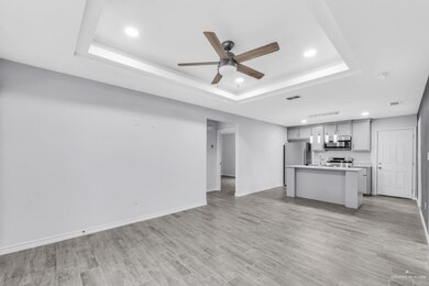 Unfurnished living room featuring a tray ceiling, recessed lighting, a ceiling fan, and light wood-style floors