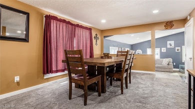 Dining space featuring light colored carpet, vaulted ceiling, and recessed lighting