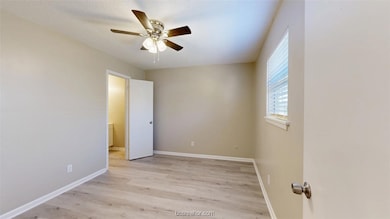 Unfurnished bedroom with baseboards, light wood-st