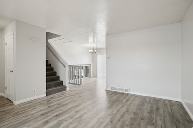 Unfurnished living room featuring light wood-style floors, a chandelier, and stairs