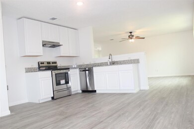 Kitchen with ceiling fan, stainless steel appliances, white cabinets, and light wood-type flooring