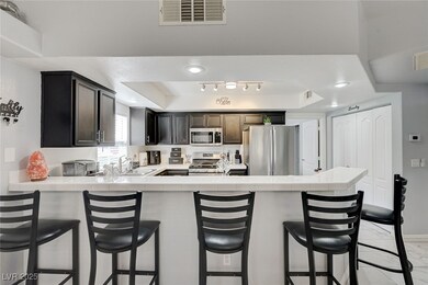 Kitchen featuring a peninsula, a raised ceiling, tile counters, and a breakfast bar