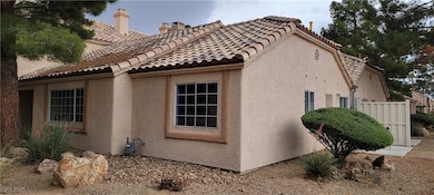 View of side of home with stucco siding, a tile ro