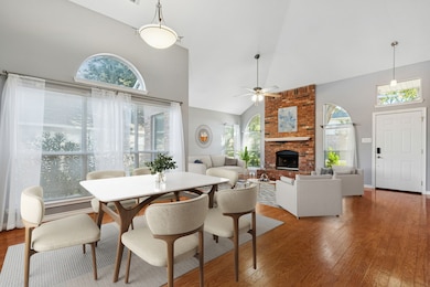 Virtually Staged Dining and Living Room featuring high vaulted ceiling, hardwood floors, a fireplace, and ceiling fan.