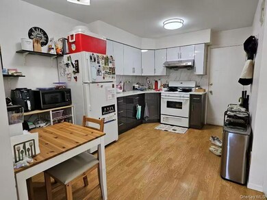 Kitchen featuring white cabinetry, light countertops, light wood-style flooring, white appliances, and gray cabinetry