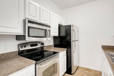 Kitchen featuring a sink, white cabinets, applian