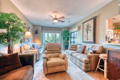 Living room with light colored carpet, a textured ceiling, and a ceiling fan