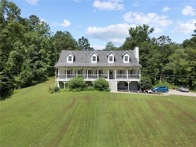 View of front facade featuring a porch, a front yard, stairs, and a chimney