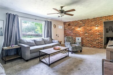 Living room featuring ceiling fan, brick wall, and carpet