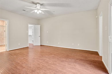 The spacious primary bedroom offers excellent natural light, enhanced by sliding glass access to the courtyard (not shown in this photo). To the left, you’ll find a generous walk-in closet with built-ins, and the additional doorway leads to the ensuite bathroom.