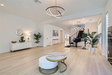 Living area with recessed lighting, arched walkways, light wood-type flooring, a chandelier, and stairway