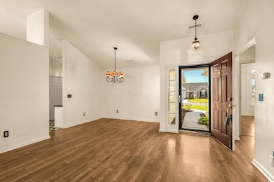 Entryway with wood finished floors, an inviting chandelier, baseboards, and visible vents