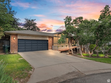 View of front facade with driveway, brick siding, a garage, and a lawn