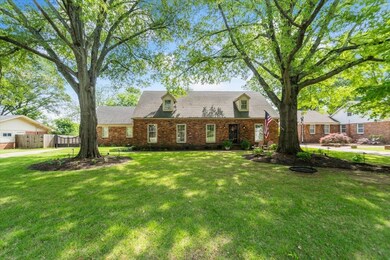 Cape cod-style house with brick siding, a front la