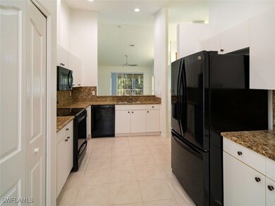 Kitchen with white cabinetry, sink, dark stone cou